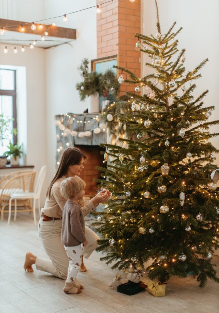 クリスマスツリーに飾り付けをする母親と子供